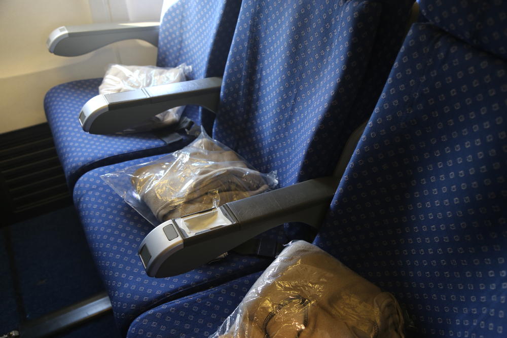  brown wrapped blankets on blue seats of airplane.