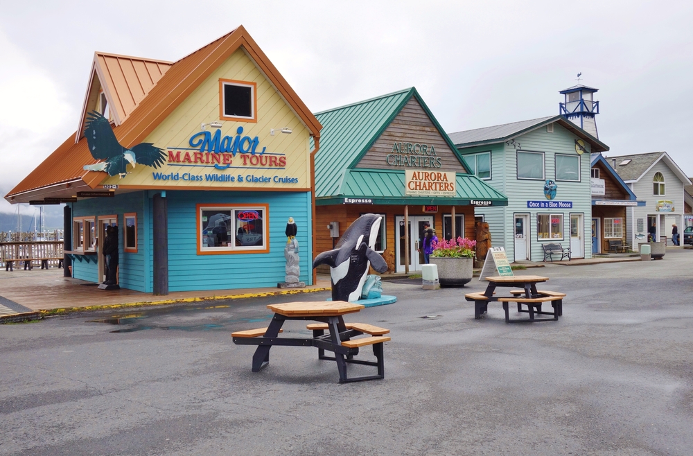 towns in Alaska picturesque downtown Seward with colorful buildings. Two wooden picnic table in foreground.