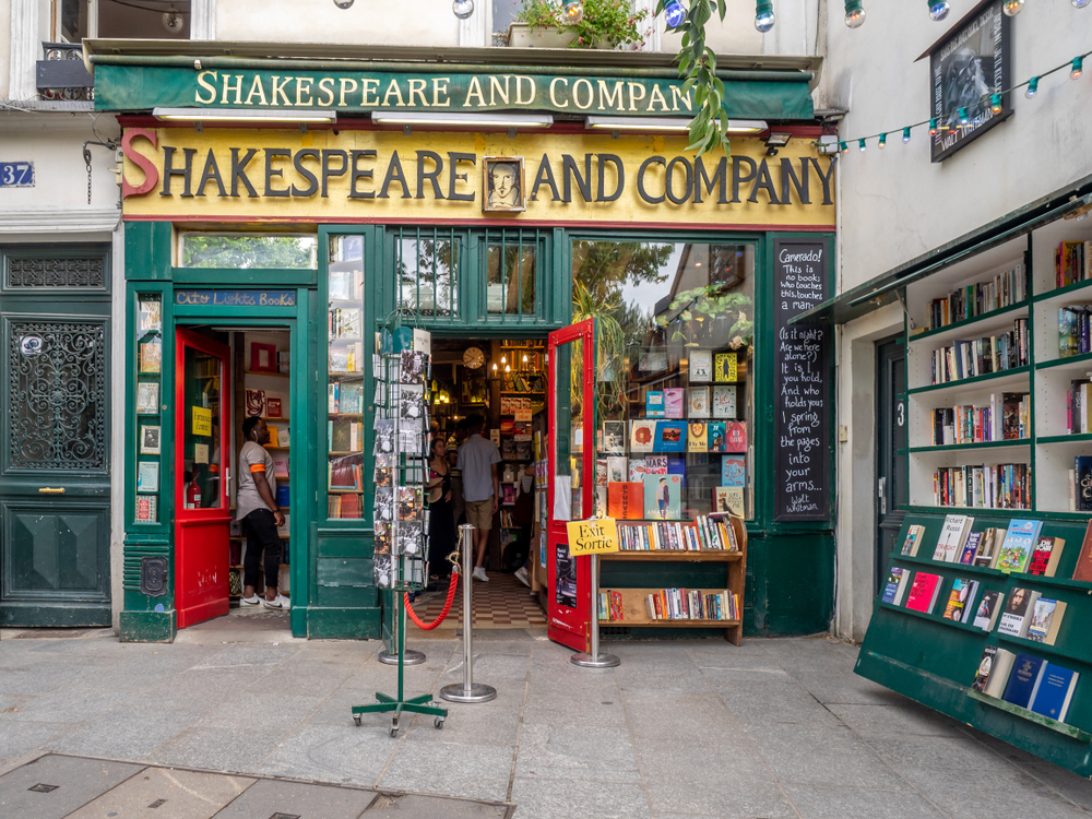 Unusual things to do in Paris Shakespeare & Co bookstore with red doors swung open and books on display everywhere.