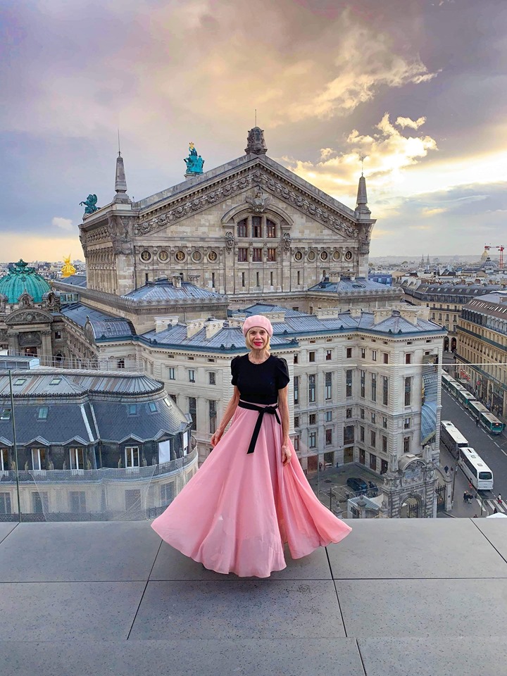 Woman in pink shirt and beret standing on the Rooftop Terrace At Galleries Lafayette overlooking Paris.