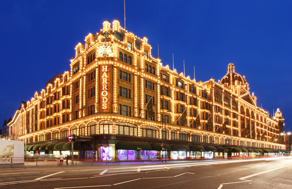 Dusk over the Harrods store with many lights along the outside.