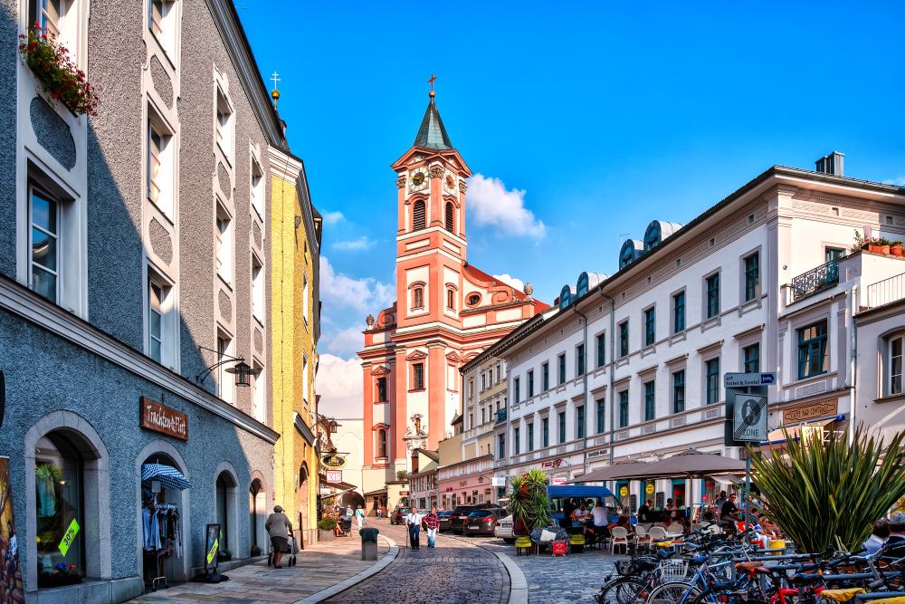 Looking up a street to the pink and white St Paul Parish Church in Passau, Germany.