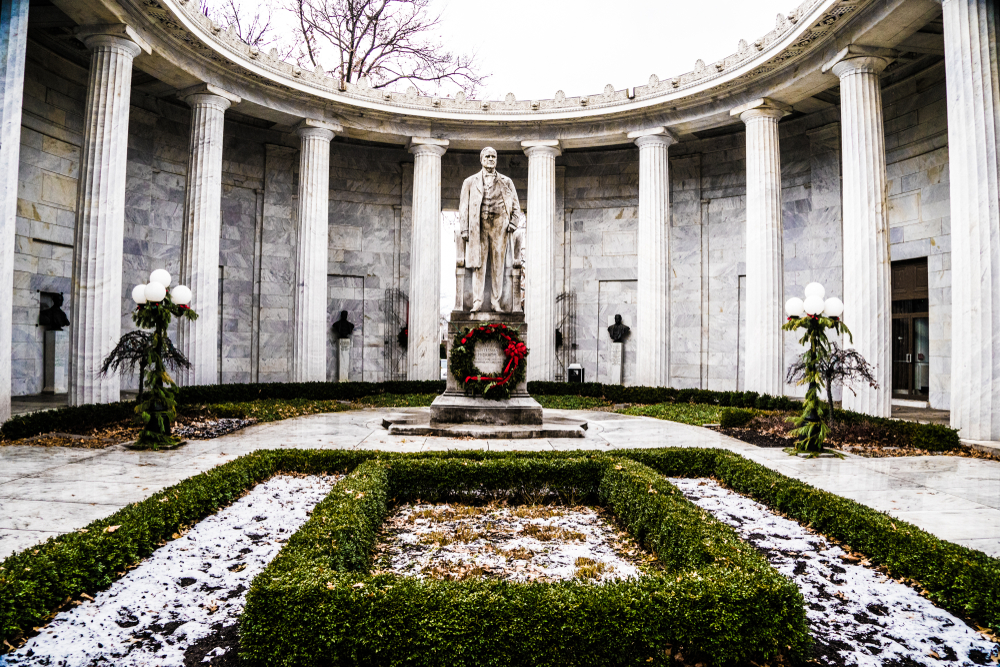 White marble statue of man surrounded by white building with many while columns. Wreath at base of statue. Green hedges in foreground.

 things to do in Youngstown