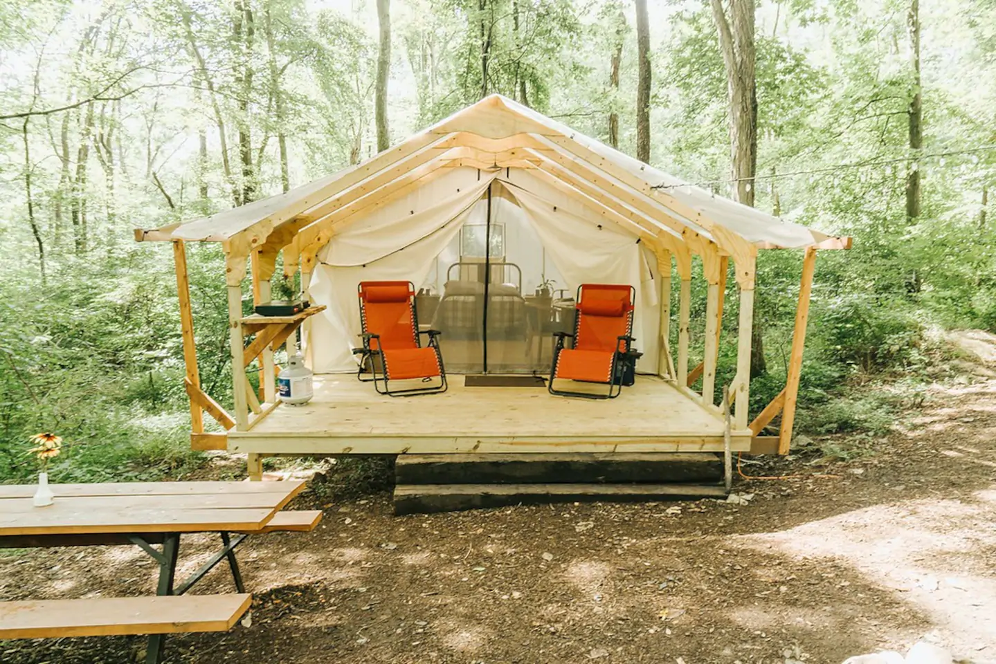 Glamping tent in Pennsylvania with one bed and a few chairs.