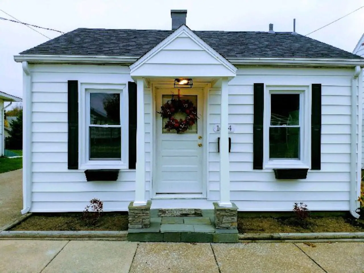 Charming white bungalow with black shutters in Erie, PA. This charming tiny house is one of the best Pennsylvania Airbnb around!