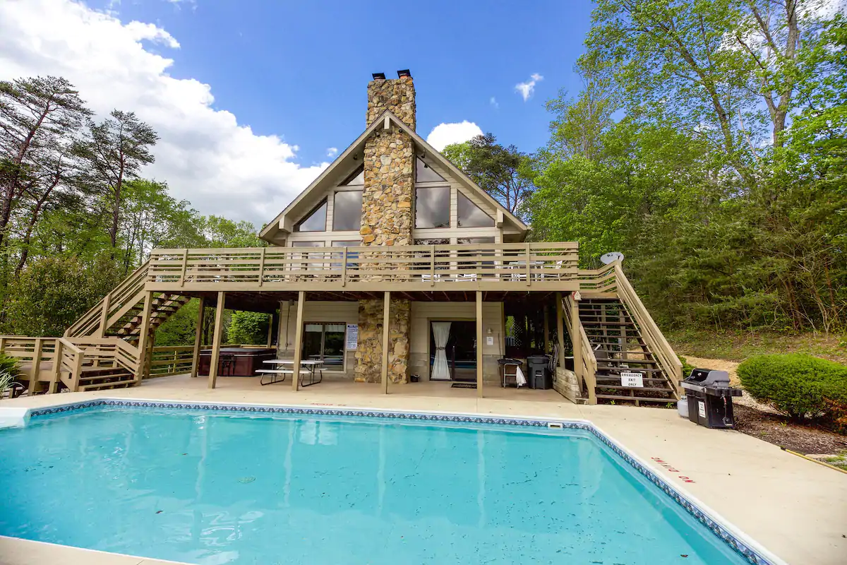 Photo of a sprawling cabin with double staircases and large pool.