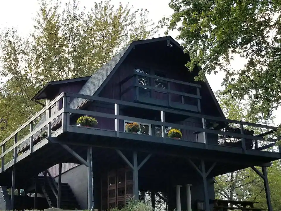 Photo of Amish made Plumb Cabin with dark wood. and pretty plants on the patio.. One of the best cabin rentals in Illinois.