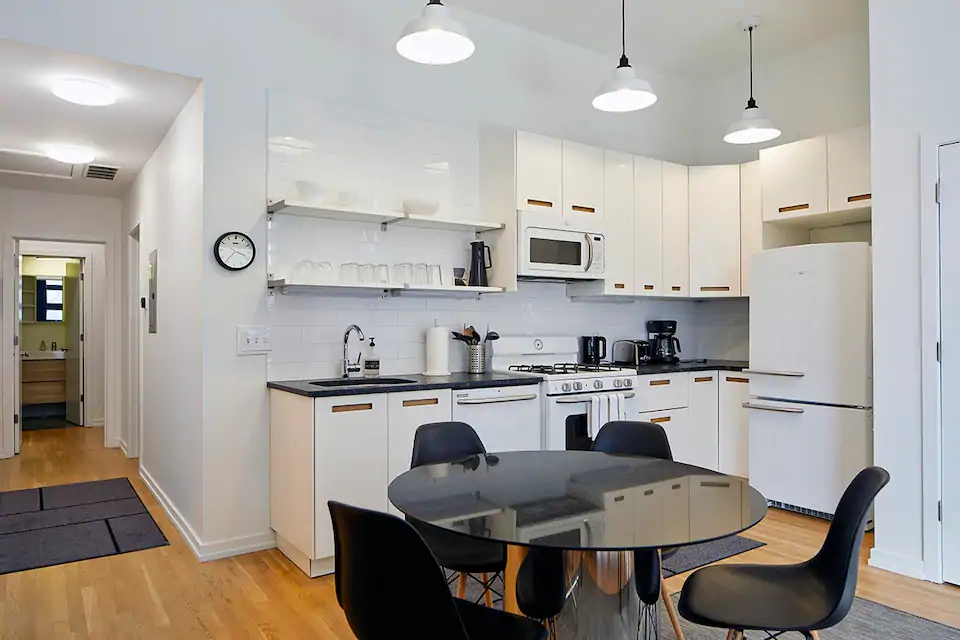 Photo of white kitchen with black counter, and black table and chairs.