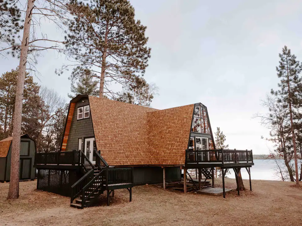 Photo of a lovely A-frame Airbnb in Minnesota on a lake, with front and side wooden decks.