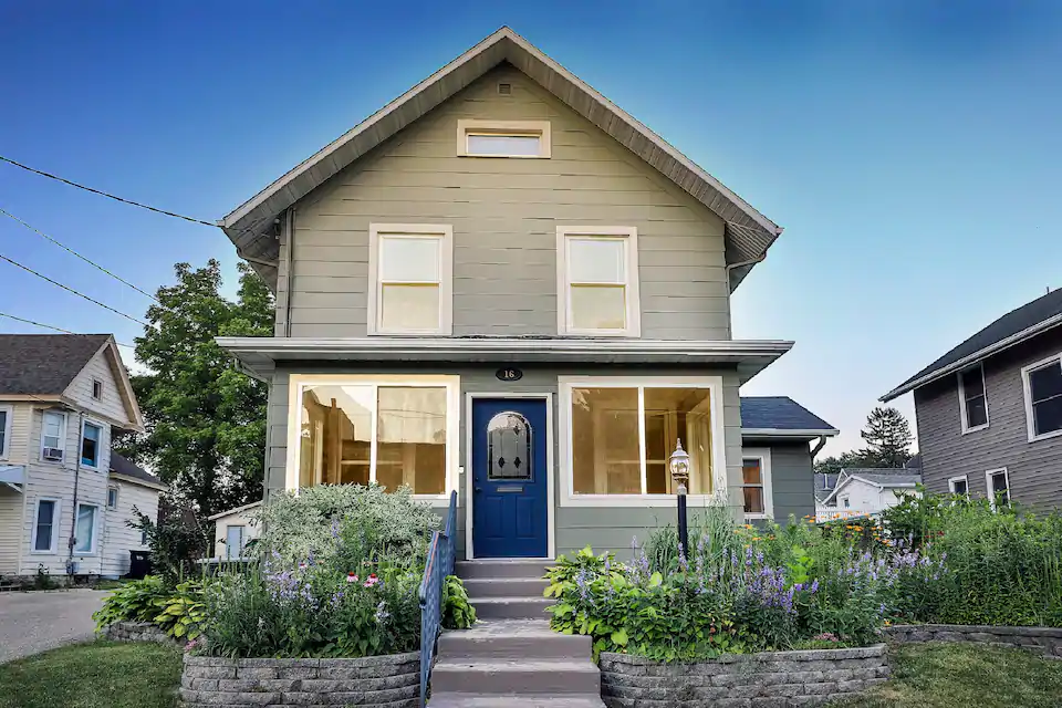 Photo of best Airbnb in Minnesota craftsman house, with taupe exterior and steps leading up to navy blue door. 