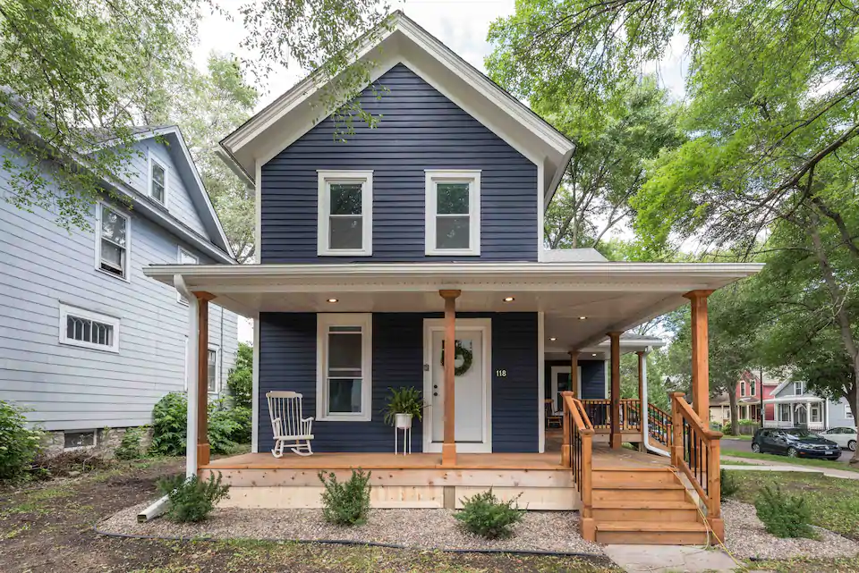 Cozy house with steel-blue siding and white rocking chair on spacious front porch. A fantastic Airbnb in St Paul.