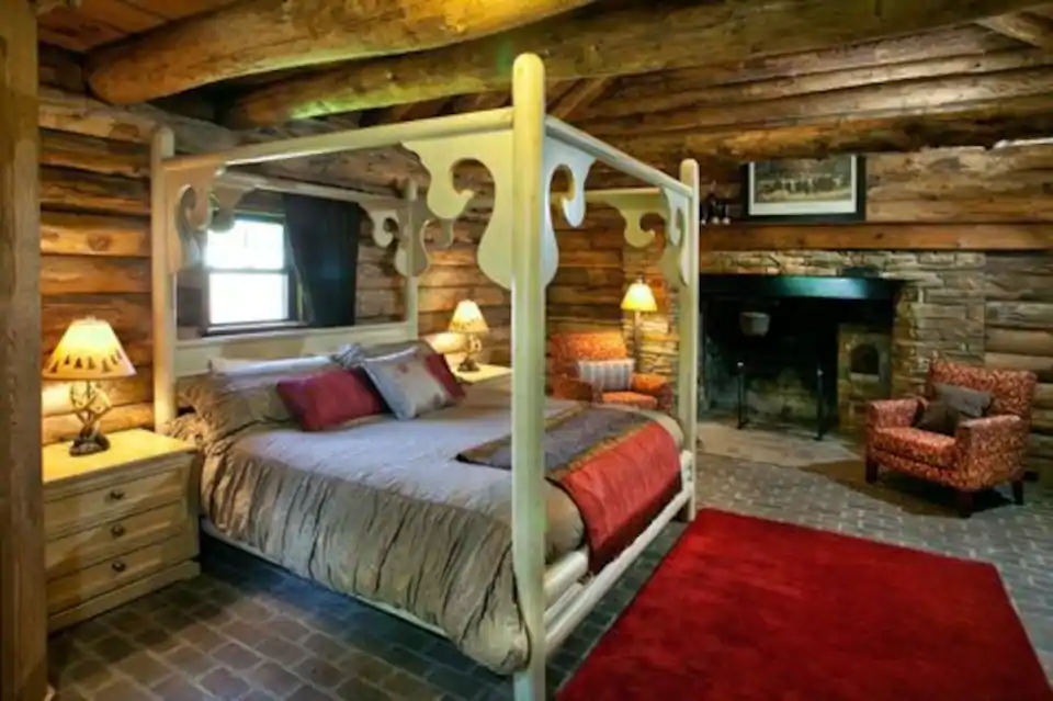 Queen-sized bed in log cabin with nice window and red carpet on floor, making this a great Airbnb in St Louis Missouri
