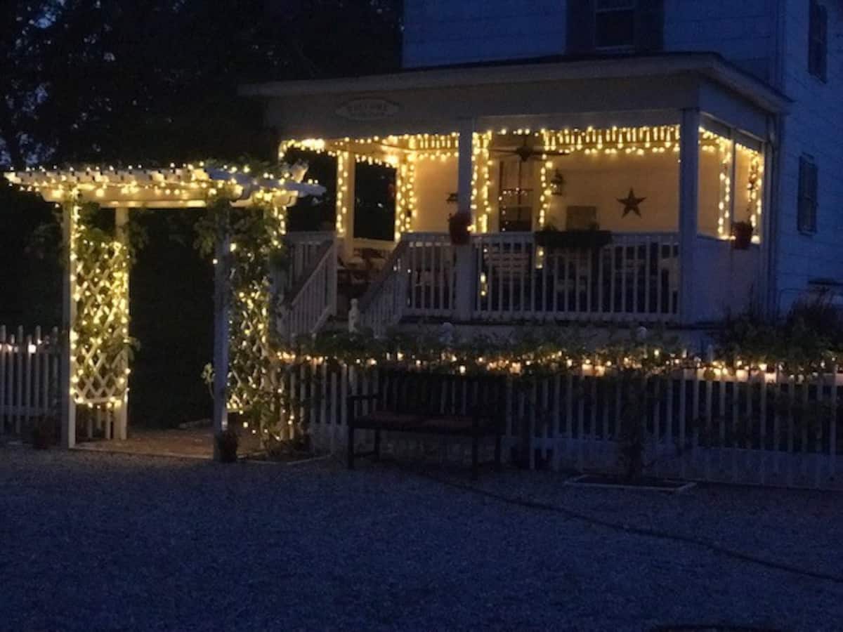 Closeup view of farmhouse at night with brilliant white lights illuminating it. This is one of the Best Delaware Airbnbs.