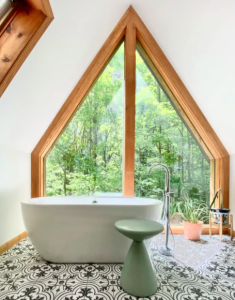 interior of A-frame cabin with floor to ceiling windows and deep bath tub