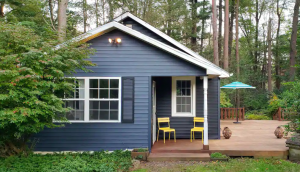 dark blue exterior of cabin with bright yellow chairs on front porch