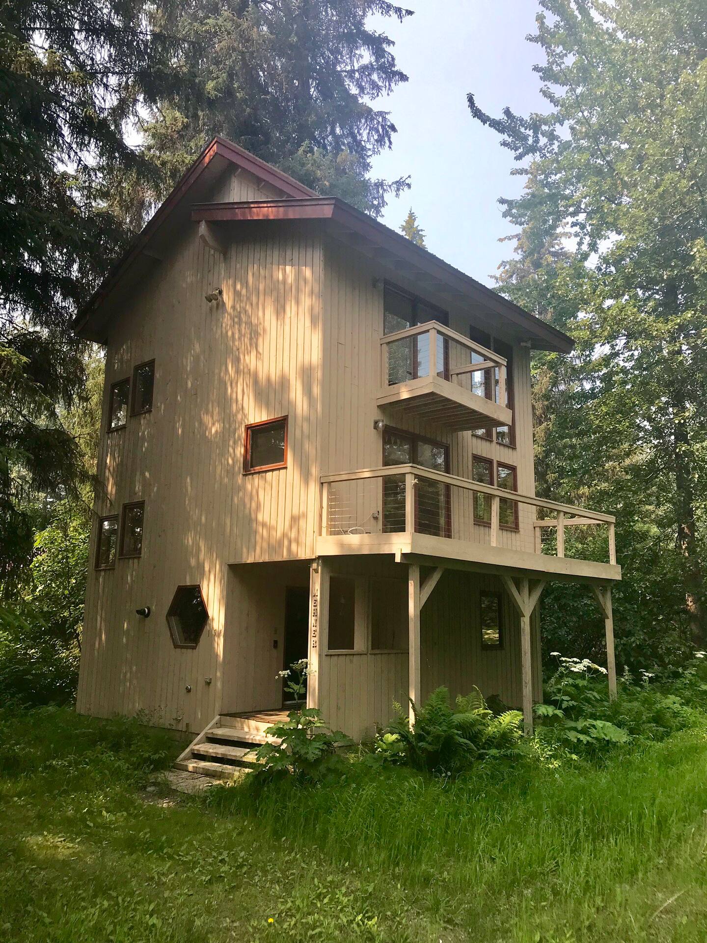 Large cabin painted beige with brown trim around every window, with balcony. One of the nicest Alaska rental cabins.