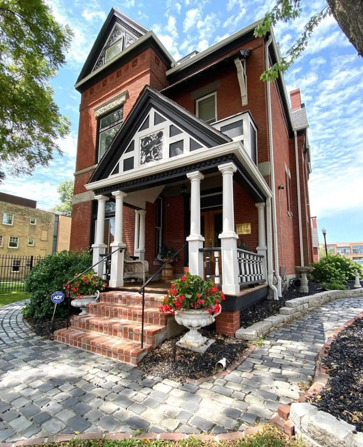 Historic three-story Queen Anne-style red brick home has beautiful white columns