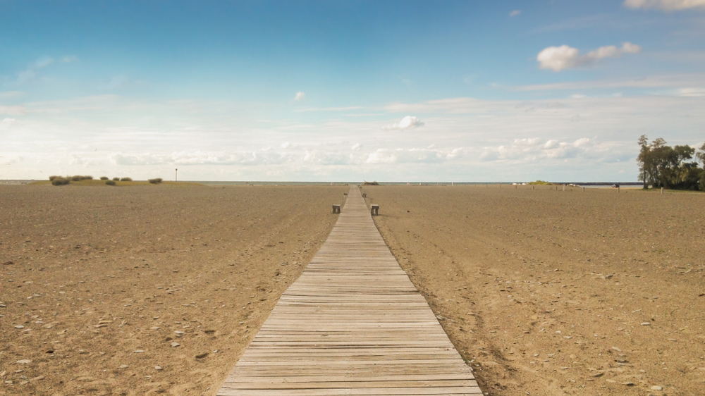 Wooden boardwalk at Conneaut Township Beach leads through the sandy beach to the horizon.