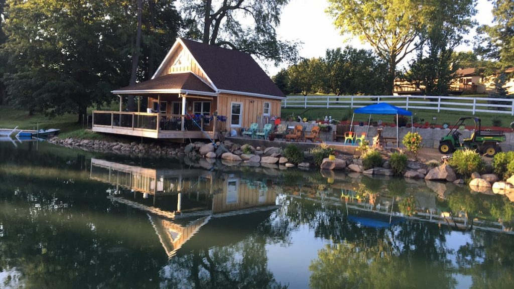 Cozy cabin on pond with large deck and colorful chairs along the pond