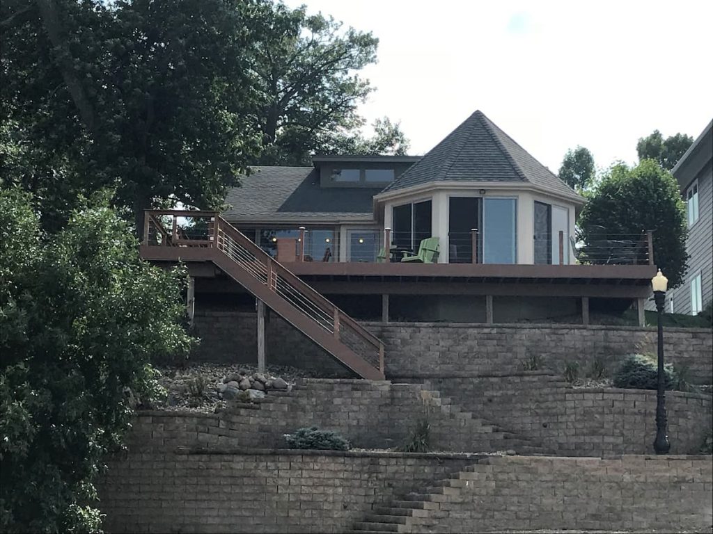 Beautiful blue cabin with wooden stairs leading down to water, and a brick wall.