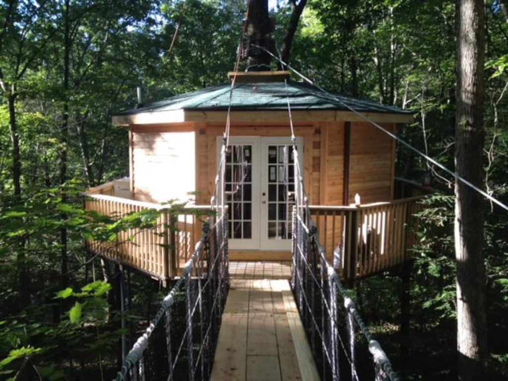 Octagonal treehouse cabin with suspension bridge leading to double-French doors is one of the coolest cabins in West Virginia.