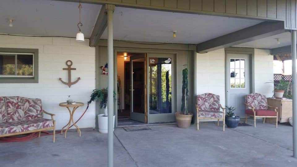 Photo of spacious entry way into a lake cabin in Nebraska with large anchor hanging on wall and various chairs to sit on under a roof for shelter.