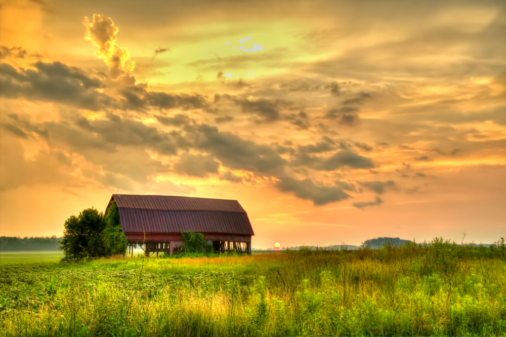 Iconic Iowa barn at sunset with sky brilliant yellow.