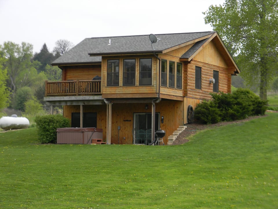 Large cabin with hot tub, deck, large windows  surrounded by nice green yard.