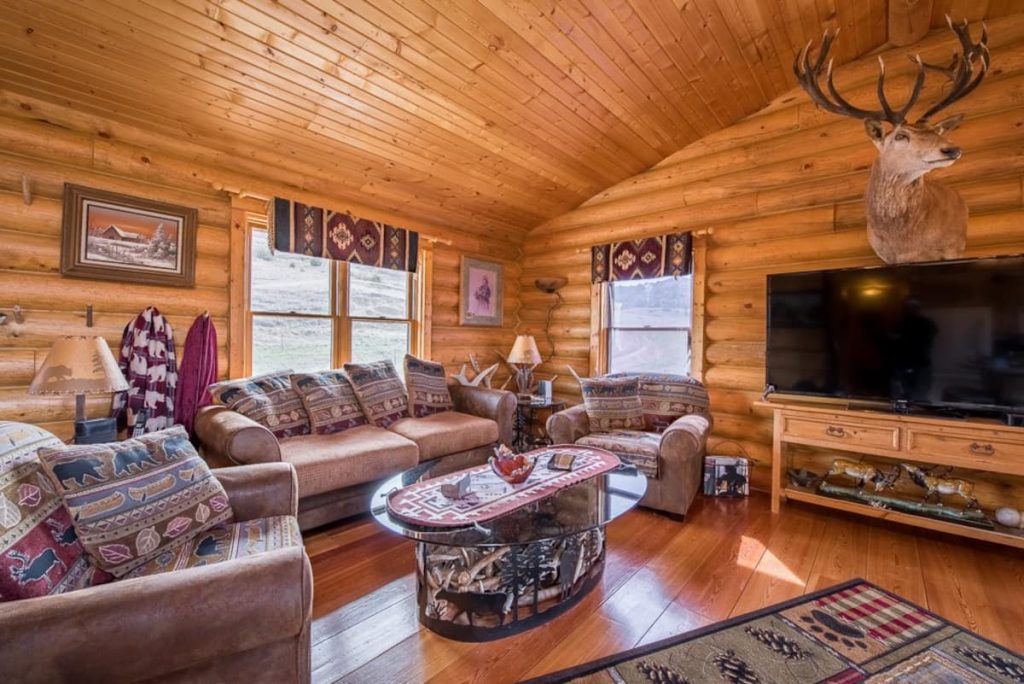 Log cabin main living space with comfy living room furniture and large screen tv, in one of the coolest cabins in North Dakota.