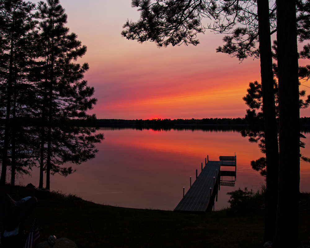 Orange sunset over a lake in Northern Minnesota. A dock in in the foreground.