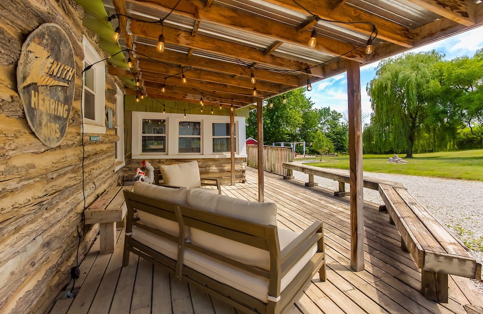 Rustic Americana front porch with wooden flooring, walls and benches.