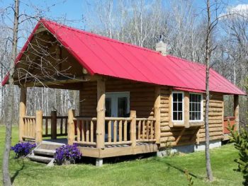 Log cabin with red rood and large front porch.