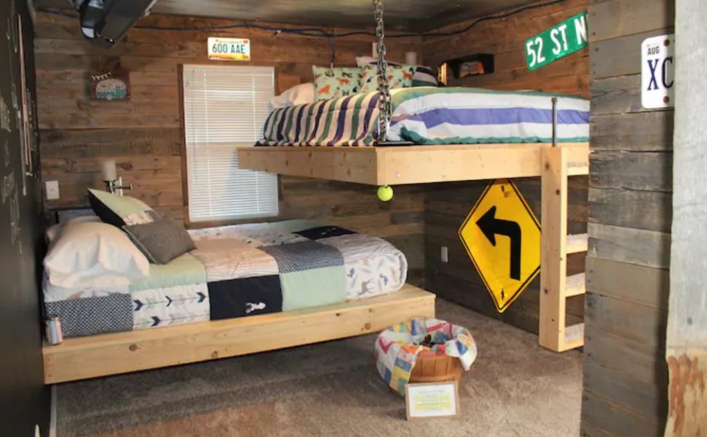 A wood paneled room decorated with traffic signs with two uniquely designed full-sized bunk beds