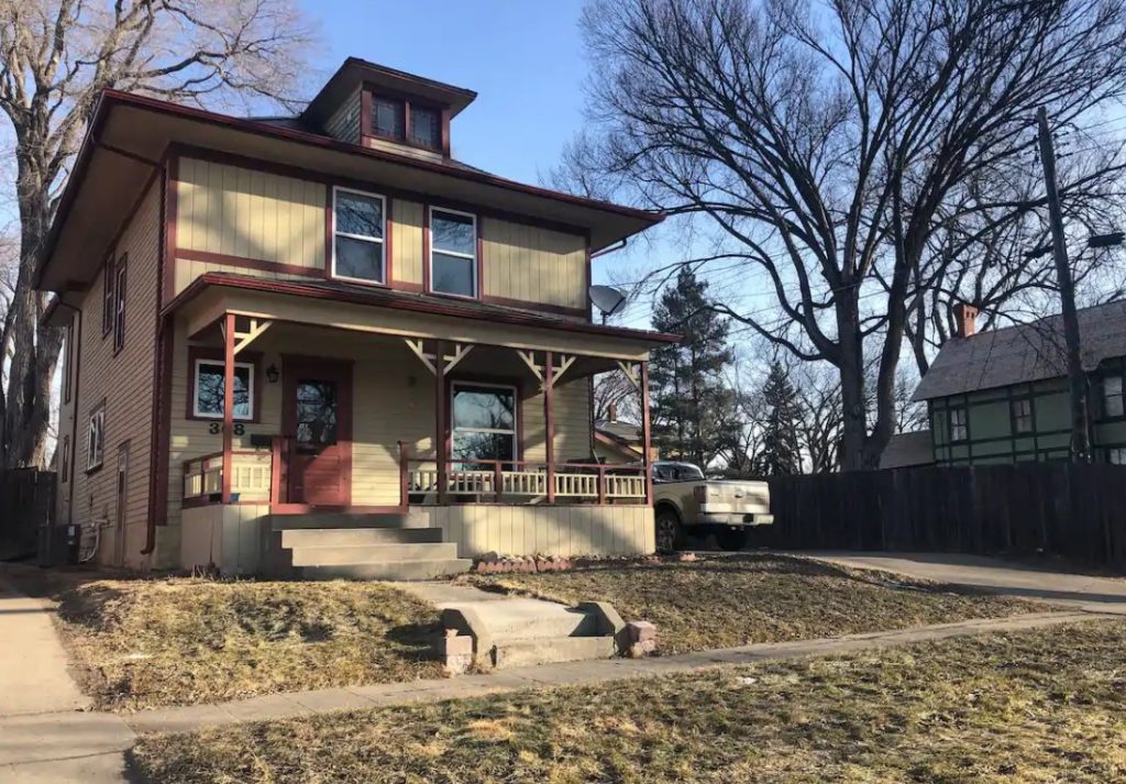 A large beautiful historic home painted tan with brick-red trim best Airbnb in North Dakota
