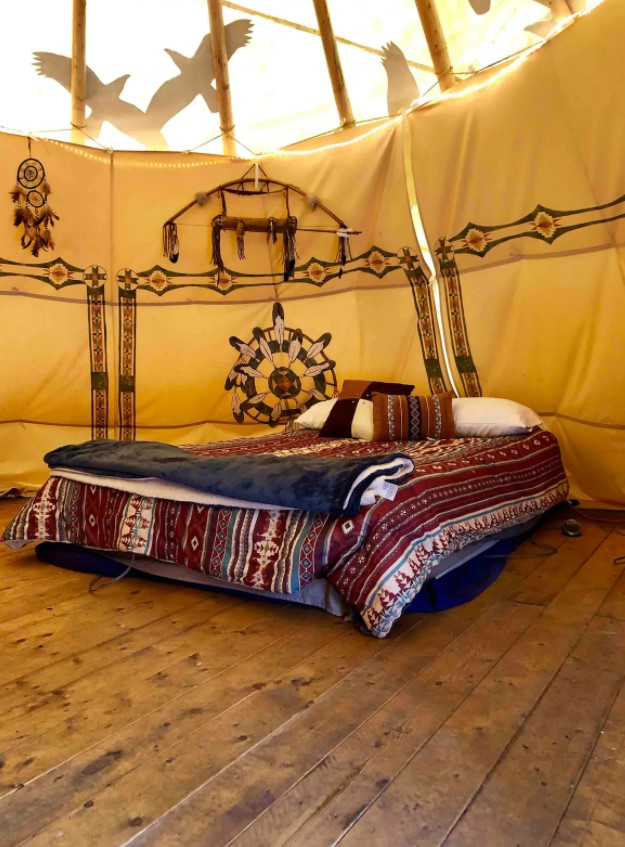 The inside of a large Native American inspired tipi with an air mattress glamping in ohio
