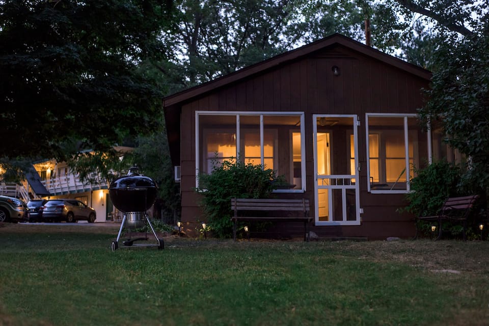 Lovely cabin in Wisconsin with trees overhead, and warm light from inside gives a cozy feel.