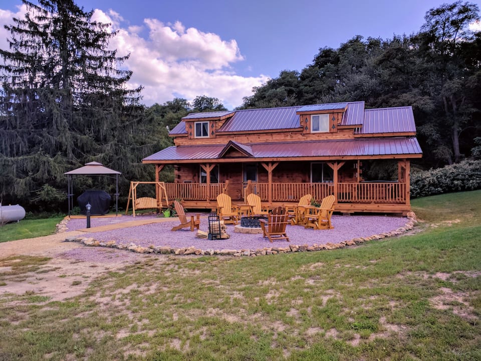 Spacious cabin with front porch that extends the entire front of the cabin. Adirondack chairs surround the fire pit in the front of the cabin.