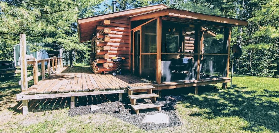 Charming rustic log cabin with screened in porch and large wooden deck.