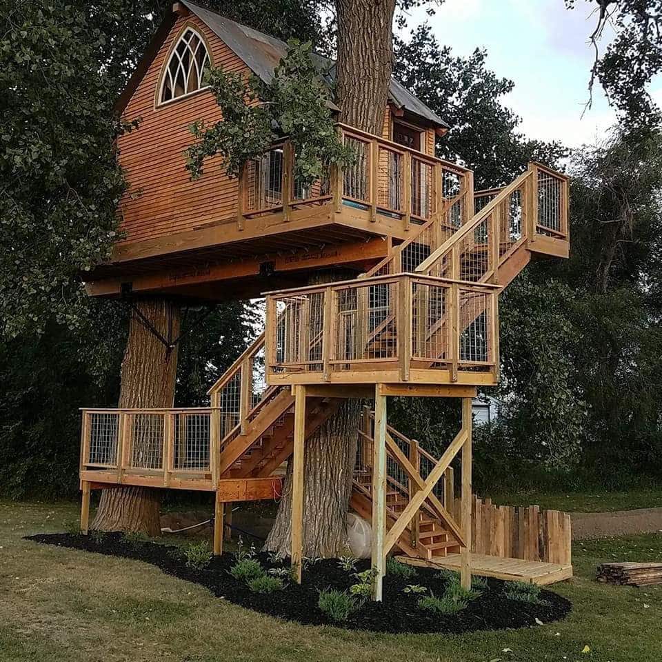 A cottage treehouse with two decks and a large staircase surrounded by trees in Nebraska
