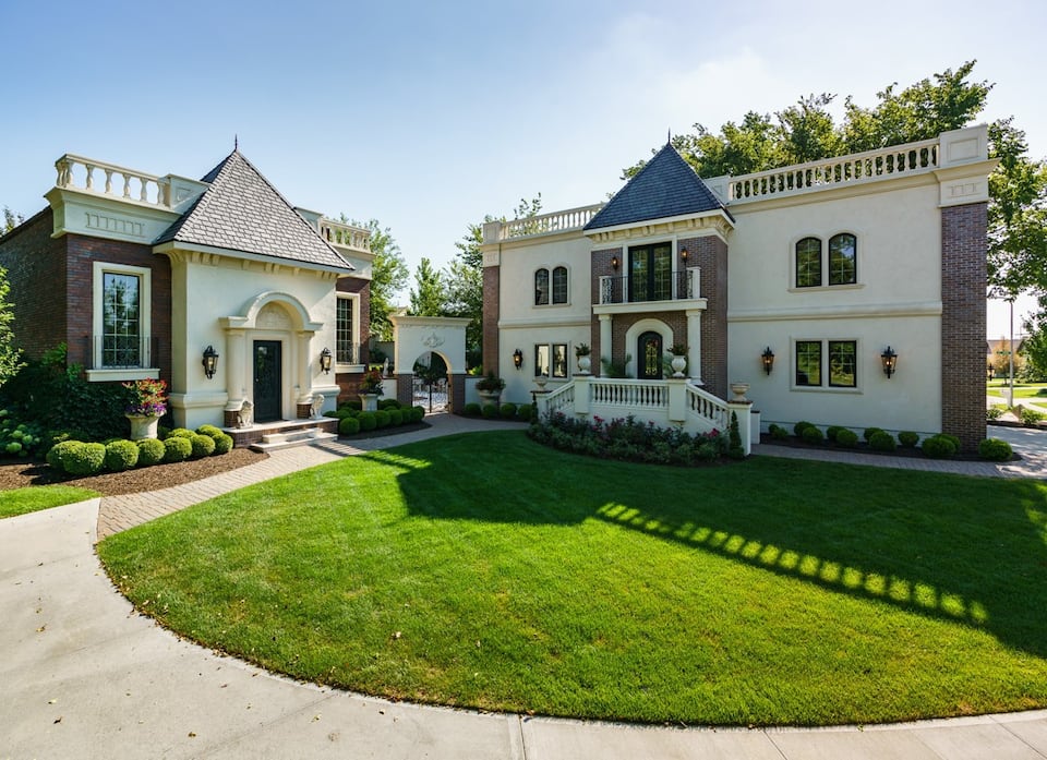 A ornately designed min mansion with a large front yard and a private walk way