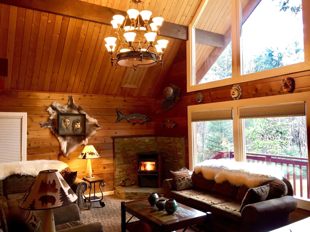 Large great room with wooden plank walls and large windows. VRBO in Alaska