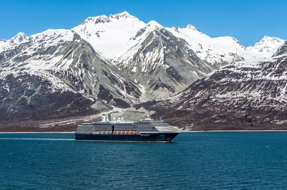 Blue Alaska cruise ship sailing past snow capped mountains