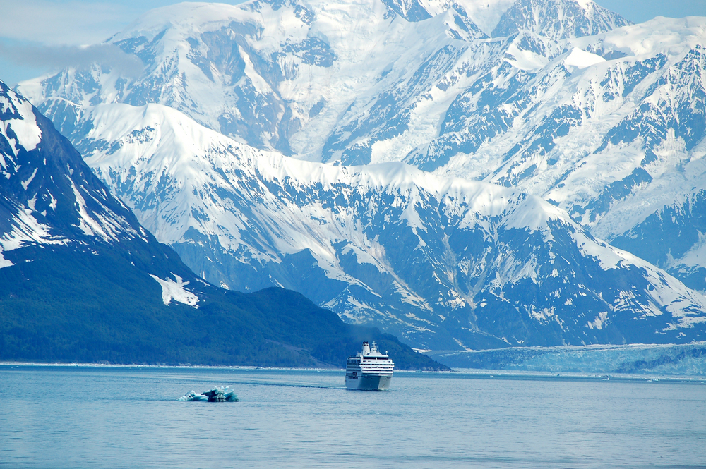 Cruise ship dwarfed by gigantic snow capped mountains.
