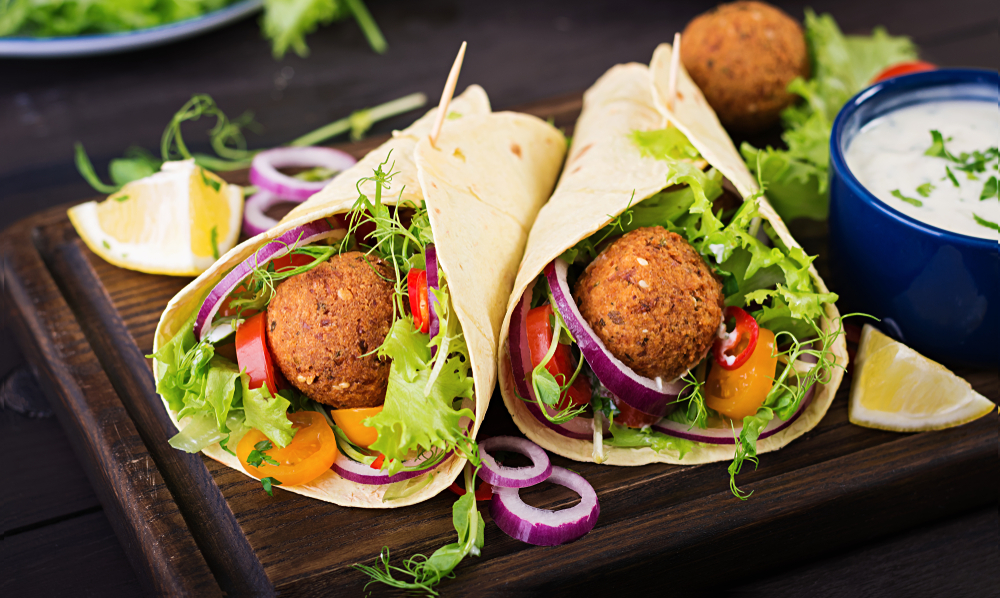 Two falafel wraps like the kind you can find at one of the best restaurants in Philadelphia. Inside the wrap there are falafel balls, lettuce, onions, peppers, and other vegetables. 