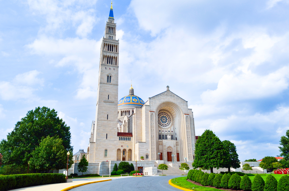 White stone church with blue domed roof and tall spire, green shrubs in foreground. Places to visit in Washington DC