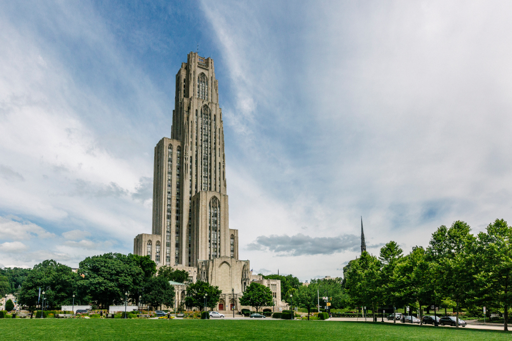 The exterior of the Cathedral of Learning, a super tall building on the campus of the University of Pittsburgh. It has gothic style architecture and in front of it is a large green lawn. Its one of the best things to do in Pittsburgh. 