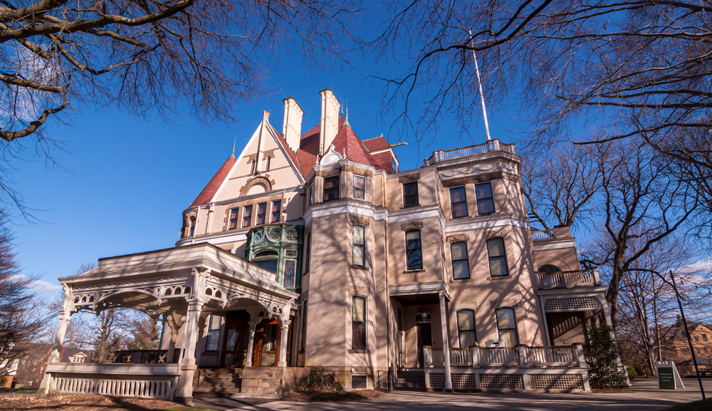 Looking up at the Clayton Mansion, also known as The Frick Art Museum, one of the best things to do in Pittsburgh. It is a Victorian style mansion that is a stone color. 