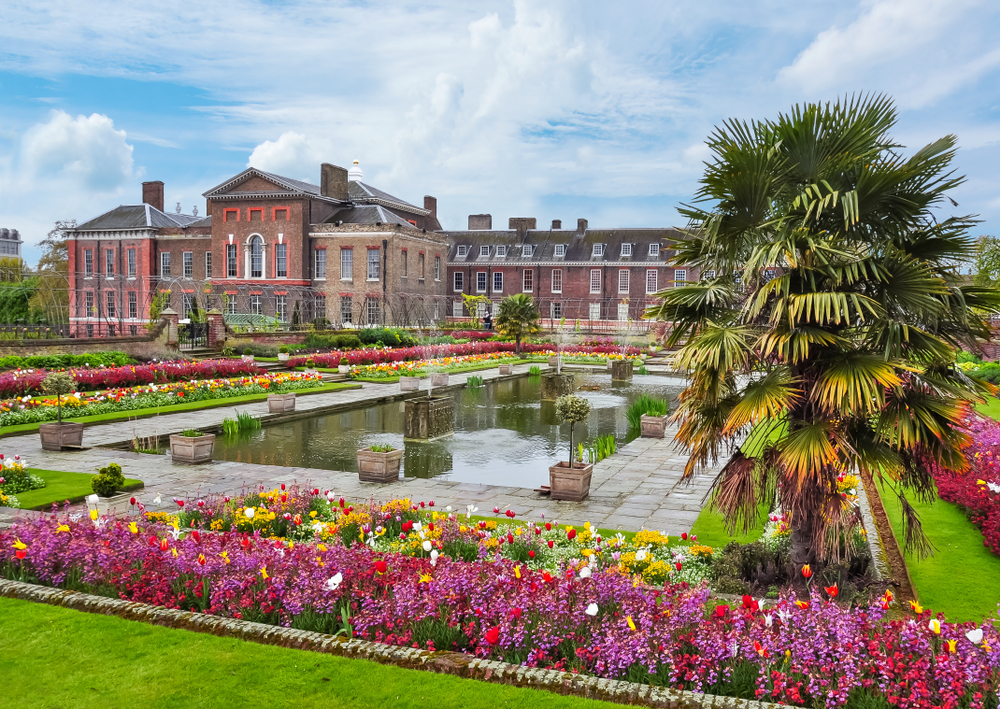 First time in London should include visiting large red palace with beautiful garden in foreground with colorful blooming flowers