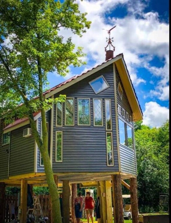 The exterior of a tree-house style cabin. It has tons of windows, and is surrounded by trees. One of the best cabins in Minnesota. 