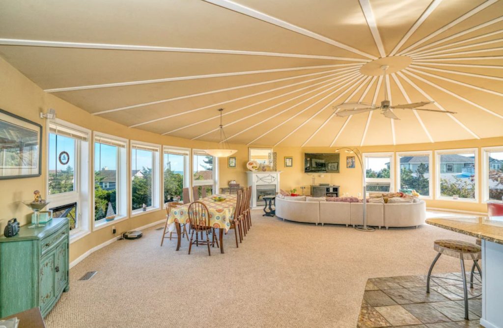 The interior of a beach house in Delaware that is round. It is painted a pale yellow and has windows all around the room that is the 